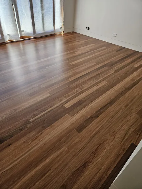 Hardwood floorboards with a satin finish in a living room with full-height windows